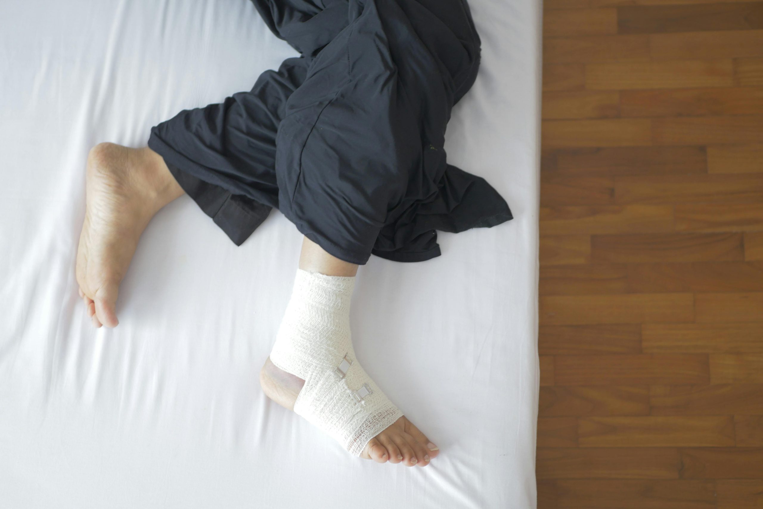 pexels photo 15068316 15068316 Top view of a bandaged foot resting on a bed, depicting injury and recovery.